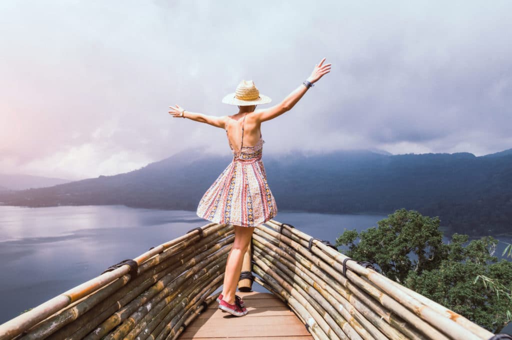 woman with arms outstretched looking out over mountains and bay