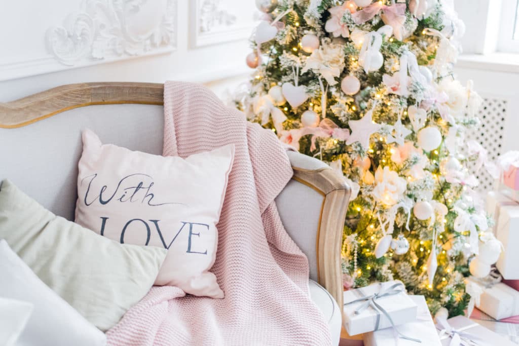Christmas or new year decoration at Living room interior and holiday home decor concept. Calm image of blanket on a vintage sofa with tree, lifghts, gifts. Selective focus.